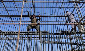 Labourers work at a construction site of a road bridge in Lahore