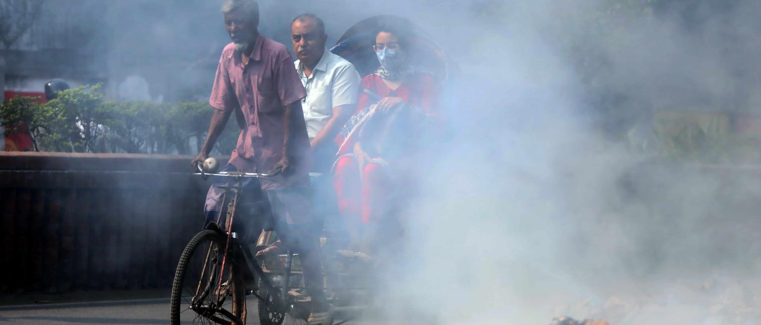 Increasing air purifier adoption could help severe air pollution illustrated by rubbish burning beside the main road in the Dhaka University area in Dhaka, Bangladesh as a rickshaw cycles past with passengers wearing face masks.