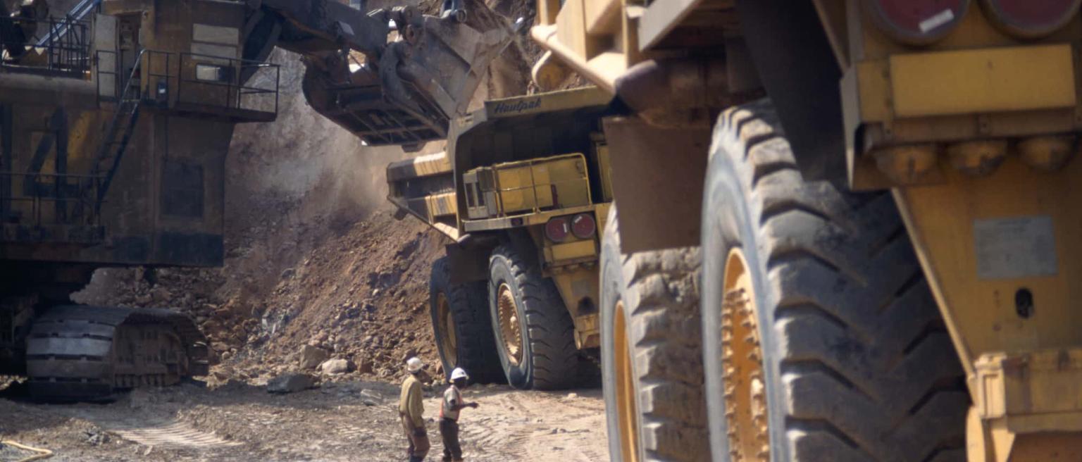 Critical minerals such as copper being mined at a copper mine in Zambia with workers and quarry trucks in action. 