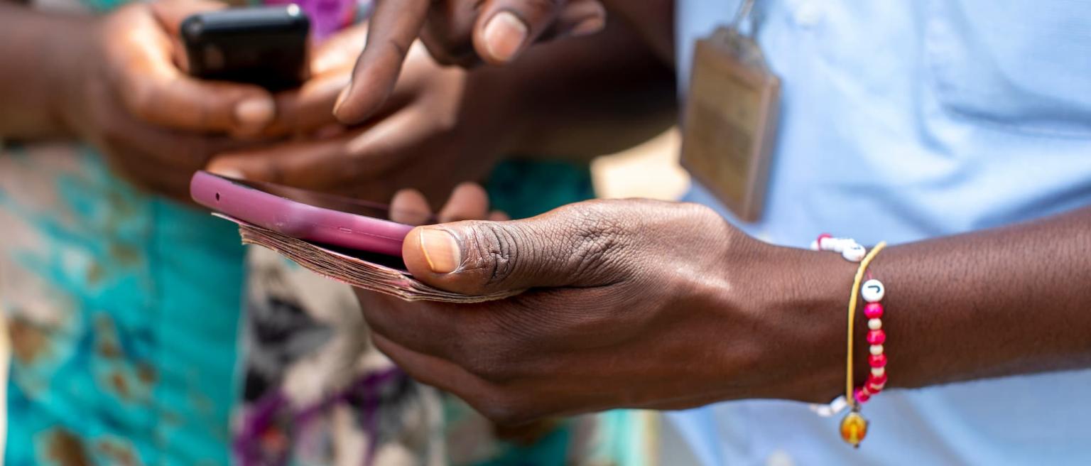 Two people holding mobile phones in Kigali, Rwanda to illustrate the digital transition to a cashless economy using mobile payments.
