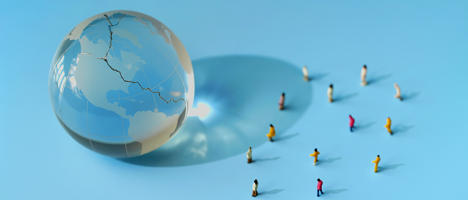 A fractured glass globe with people displaced to demonstrate the scale of forced population displacement as part of World Refugee Day.
