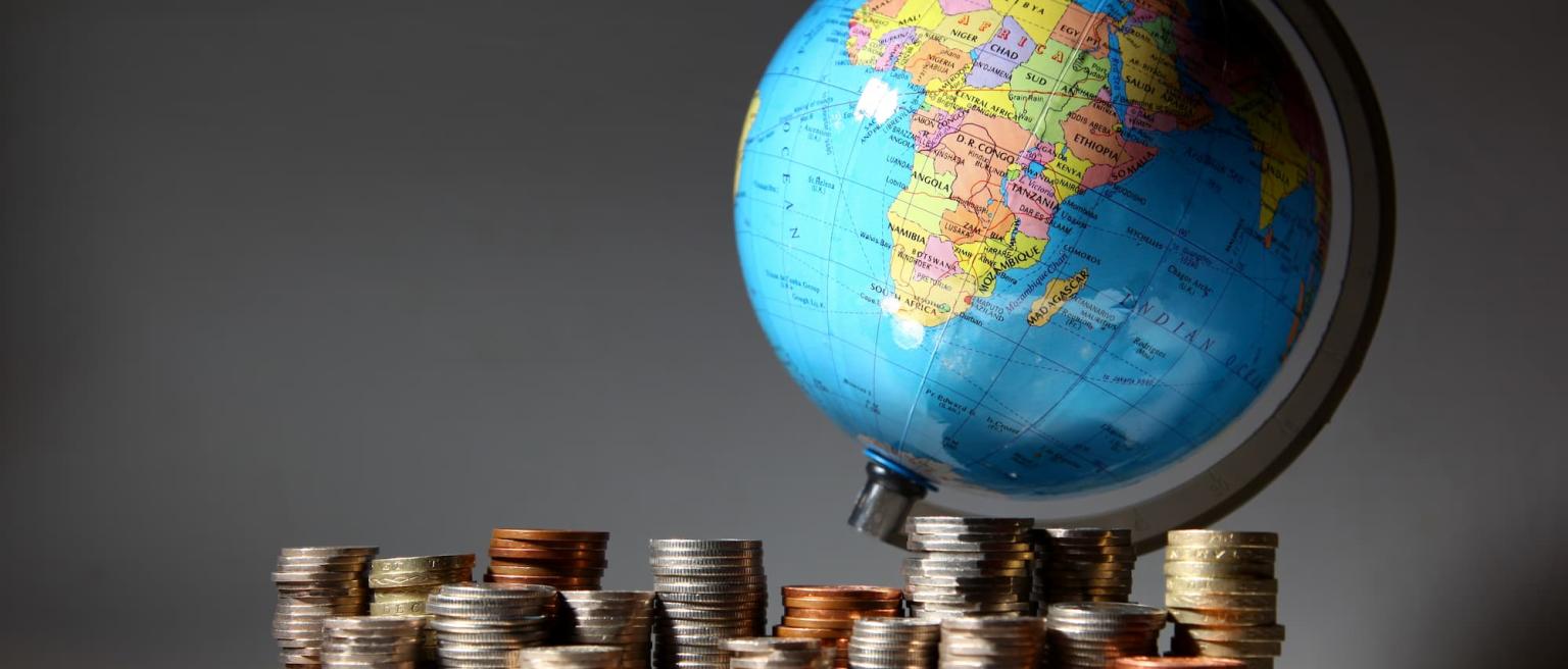 A globe surrounded by piles of coins to demonstrate the challenges of financing for development.