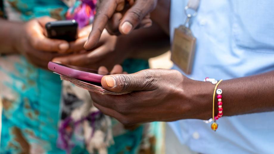 Two people holding mobile phones in Kigali, Rwanda to illustrate the digital transition to a cashless economy using mobile payments.