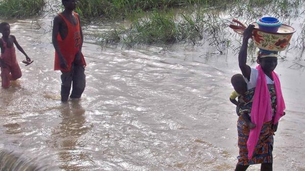 Building a more resilient Ghana with flood mitigation measures is important for villagers from a village in northern Ghana pictured fleeing floods carrying belongings and children.