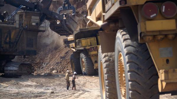 Critical minerals such as copper being mined at a copper mine in Zambia with workers and quarry trucks in action. 