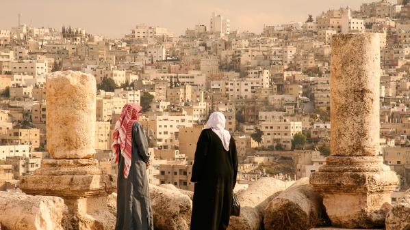 A Jordanian Couple views the Jordanian capital of Amman from the Hill of the Citadel, or Jabal al-Qal'a. Photo credits: Image Courtesy of Jennifer Hayes / Moment via Getty Images.