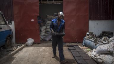 Workers process recycled plastic into blocks which can be used in road construction
