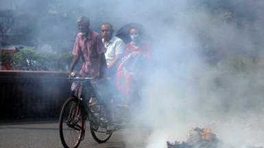 Increasing air purifier adoption could help severe air pollution illustrated by rubbish burning beside the main road in the Dhaka University area in Dhaka, Bangladesh as a rickshaw cycles past with passengers wearing face masks.