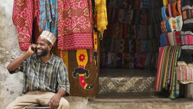 Small business owner on phone in East African market. Photo credits: Strauss/Curtis / The Image Bank via Getty Images.