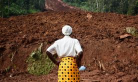 A woman stands and looks at a landslide site in eastern Uganda. Photo by ISAAC KASAMANI/AFP via Getty Images