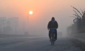 A man rides his bicycle along a road amid heavy smog conditions in Lahore on December 7, 2022. Photo by ARIF ALI/AFP via Getty Images
