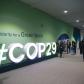 People attending the COP29 UN Climate Change Conference, walking past the event tagline written on the wall 'In solidarity for a Green World'g past the 