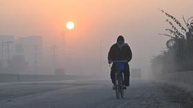 A man rides his bicycle along a road amid heavy smog conditions in Lahore on December 7, 2022. Photo by ARIF ALI/AFP via Getty Images