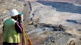 A man surveys a pit with an engineering instrument