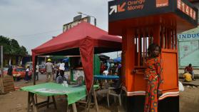 A woman dressed in orange withdraws money at an Orange Money cashier booth