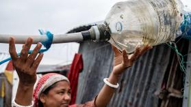 A woman uses a homemade water bottle to pipe water in rural Bangladesh while economies of scale can be used to leverage infrastructure pricing.