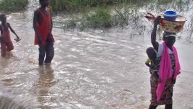 Building a more resilient Ghana with flood mitigation measures is important for villagers from a village in northern Ghana pictured fleeing floods carrying belongings and children.