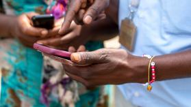 Two people holding mobile phones in Kigali, Rwanda to illustrate the digital transition to a cashless economy using mobile payments.