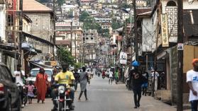 People walking down a busy street with businesses reliant on electricity in Freetown, Sierra Leone.
