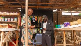 Young trader in his market stall transacting business with his customers in a market in Enugu, Nigeria