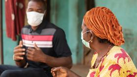 An elderly African woman and a young man wearing medical masks and chatting. Photo credit: Wirestock / iStock / Getty Images Plus via Getty Images.