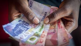 A man holds a bundle of Ghanaian Cedi banknotes. Photo credit Cristina Aldehuela/Bloomberg Creative Photos via Getty Images.