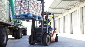 Fork lift truck loading a pallet of tinned tomatoes onto a lorry outside a large food distribution warehouse. Photo credit: Alistair Berg / DigitalVision.