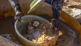 An artisanal miner sifts through crushed ore powder for gold particles