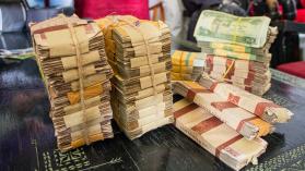 Bundles of old and worn legal tender notes of Ethiopian currency in bundles on the table with pita rope.Stacks of bills in packages on the table - by Jose Javier Ballester legua / Moment / via Getty Images