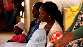 Two pregnant women and their children wait to be seen in a queue at a clinic in Mozambique