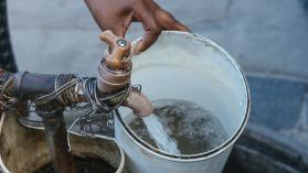 A resident fills a plastic container with water from a communal tap in a township in South Africa. Photographer: Waldo Swiegers/Bloomberg