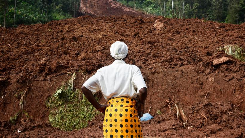 A woman stands and looks at a landslide site in eastern Uganda. Photo by ISAAC KASAMANI/AFP via Getty Images
