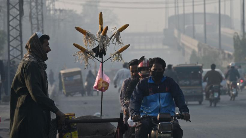 Man sells corn to customers amid road full of smog in Lahore