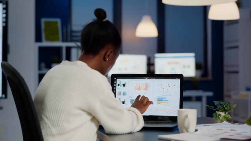 A woman types at her laptop, working in an office.