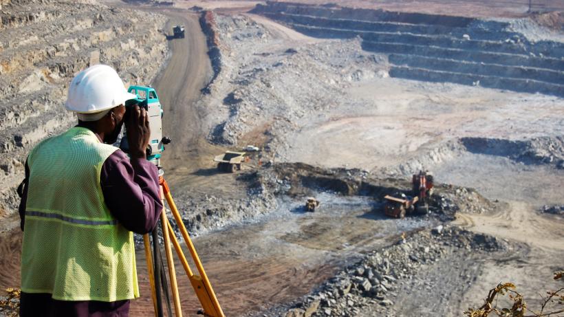 A man surveys a pit with an engineering instrument