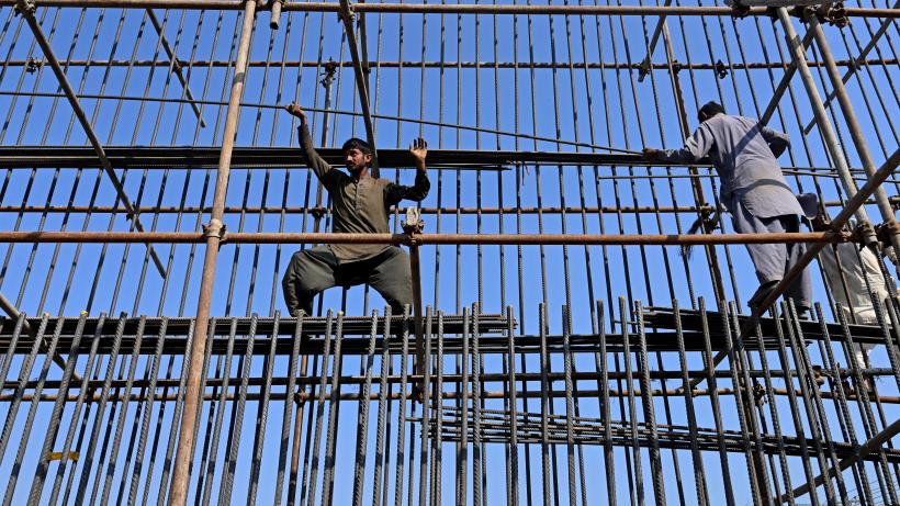 Labourers work at a construction site of a road bridge in Lahore