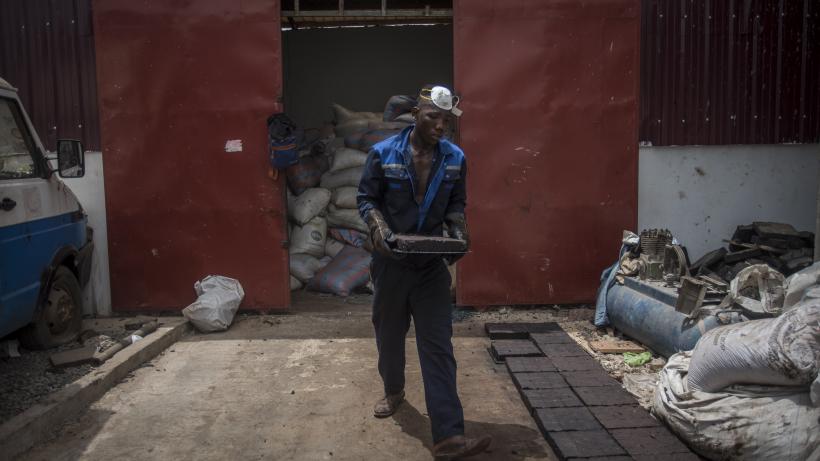 Workers process recycled plastic into blocks which can be used in road construction