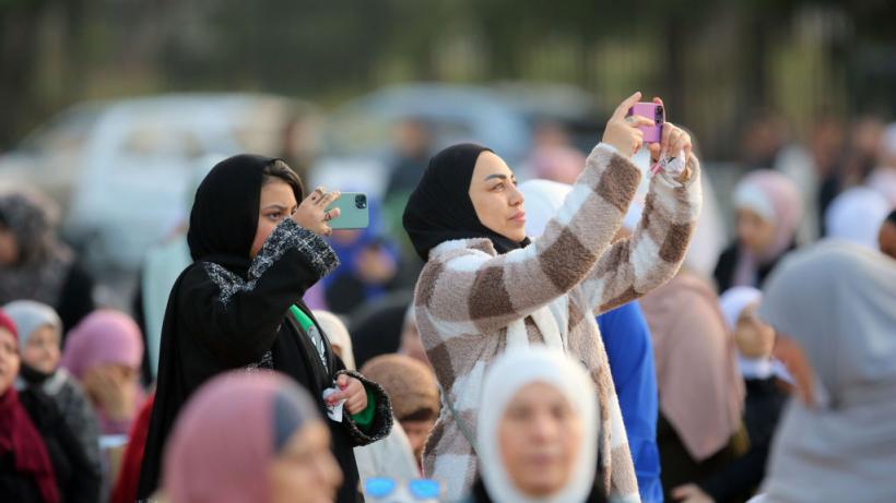 Women in Jordan taking photos as Muslims gather on the first day of the Eid al-Fitr holiday.