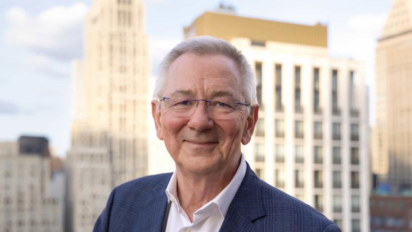 Sir Andrew Steer, a man wearing glasses and a suit, standing with buildings in the background.