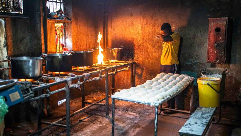 Electrification in rural South Africa is slow, demonstrated by a man overlooking a kitchen using fire to cook.