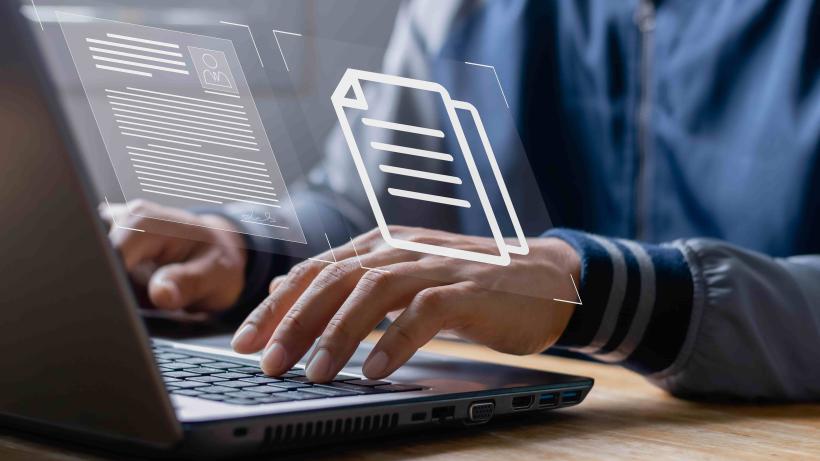 An image of a person working on a laptop with data graphics superimposed to demonstrate how AI is changing the way labour force surveys are analysed in Zambia.