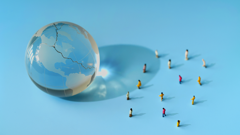 A fractured glass globe with people displaced to demonstrate the scale of forcibly displaced populations as part of World Refugee Day.