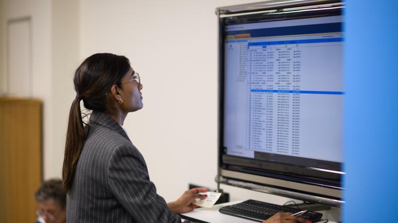 Professional Indian female doctor reviewing digital records on a monitor in an office setting 