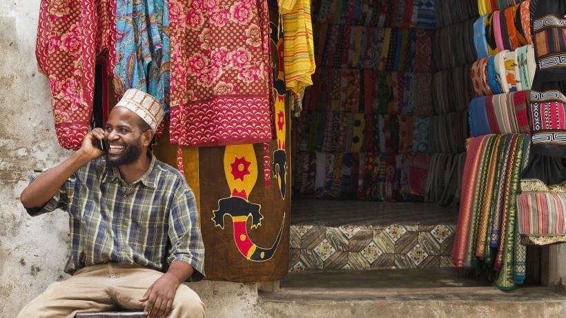 Small business owner on phone in East African market. Photo credits: Strauss/Curtis / The Image Bank via Getty Images.