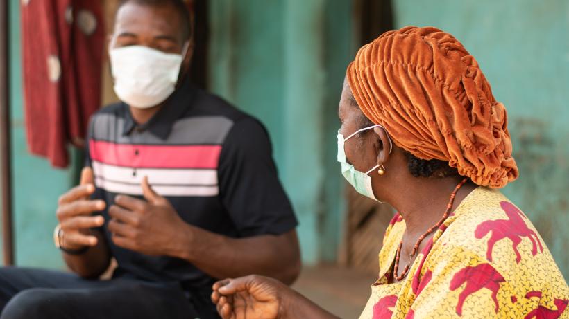 An elderly African woman and a young man wearing medical masks and chatting. Photo credit: Wirestock / iStock / Getty Images Plus via Getty Images.