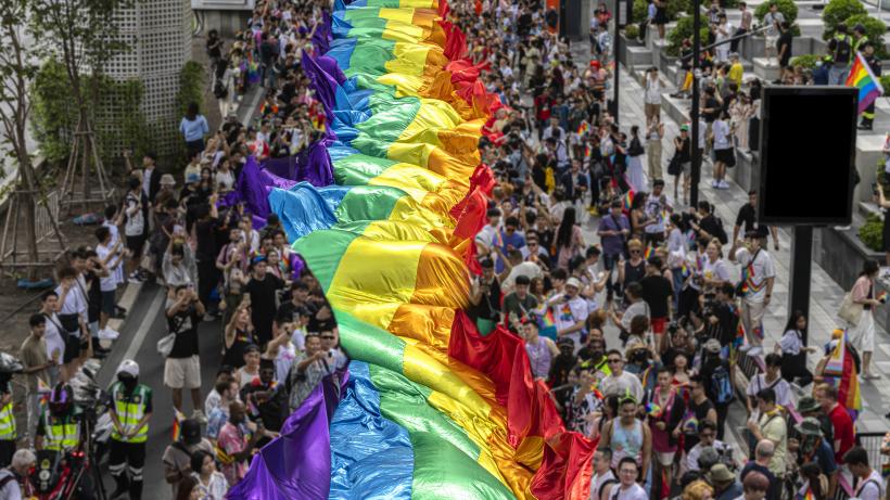 Group of People Celebrating Gay Pride Parade- Pride Month and Parade-People marching with the rainbow LGBTQ+ flag. Photo credit: Chuchart Duangdaw / Moment via Getty Images.