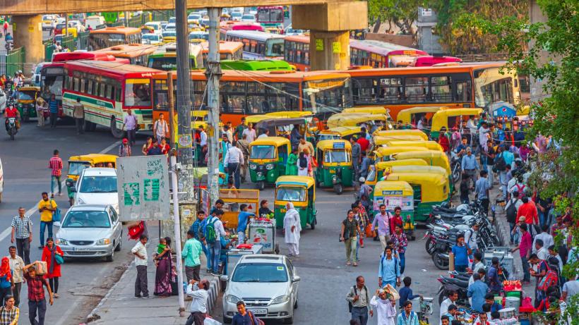 A busy street in New-Delhi, India. A view of people, buses and Tuk Tuks.