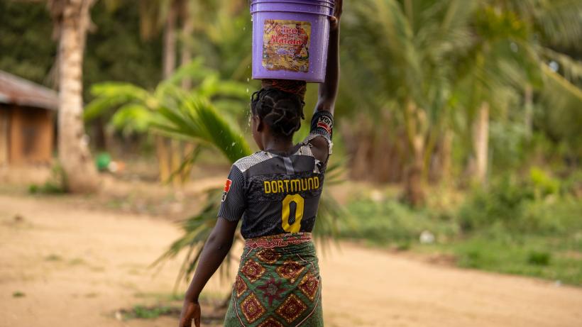 Palma, Mozambique: A young African girl balances a container of water on her head in Cabo Delgado.