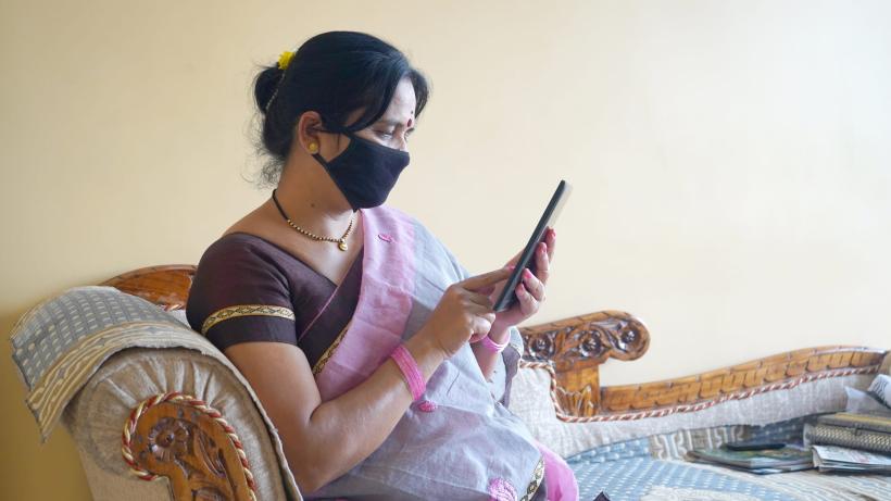 Indian woman with face protective mask reading news on tablet. by CR Shelare&nbsp;/&nbsp;Moment / via Getty Images