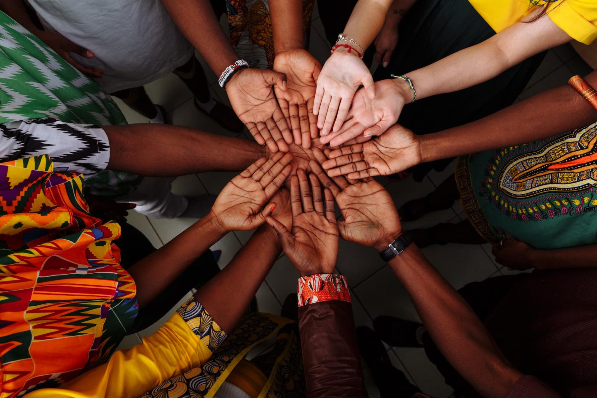 Hands and palms of local researchers in a circle to demonstrate research impact.